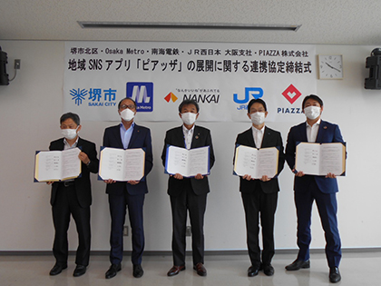 締結式で（左から、Osaka Metro 執行役員 堀川健氏、南海電鉄 上席執行役員 まち共創本部副本部長 清原康仁氏、北区長 垂井究氏、JR西日本 常務理事 近畿統括本部 大阪支社長 水口英樹氏、PIAZZA株式会社 代表取締役CEO 矢野晃平氏）