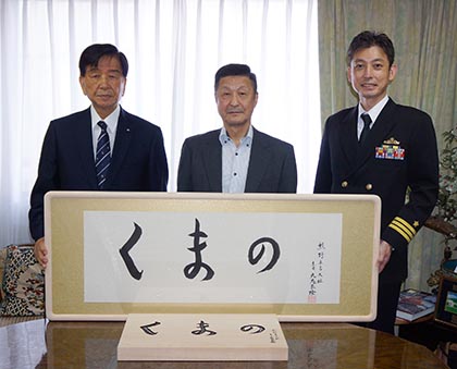 揮毫を前にする護衛艦「くまの」ぎ装員長 櫻井敦２等海佐（右）、「くまの」後援会の吉川榮治顧問（第28代海上幕僚長）（中央）、加藤均会長（左）